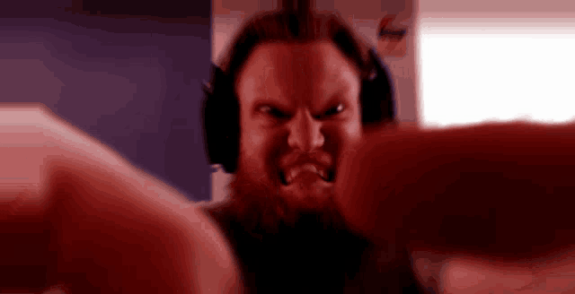 a man with a beard is wearing headphones and making a very angry face