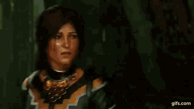 a woman is standing in a dark room wearing a necklace and a black and gold dress .