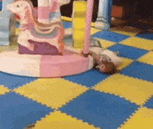 a baby is laying on the floor next to a carousel .