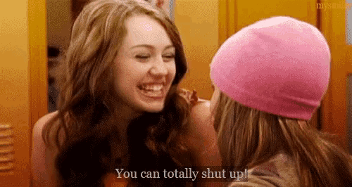 a woman in a pink hat is laughing with another woman .