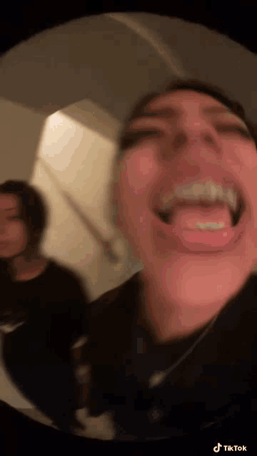 a woman is making a funny face with her tongue out while another woman stands behind her .
