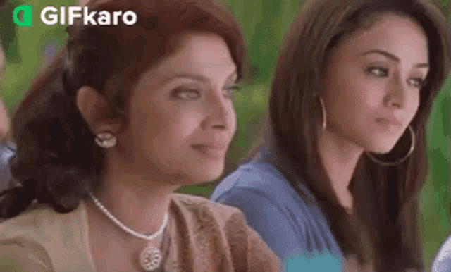 two women are sitting next to each other and looking at the camera .