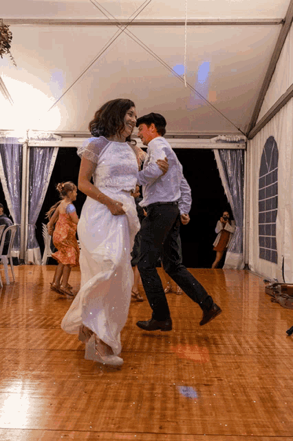 a woman in a white dress is dancing with a man in a suit