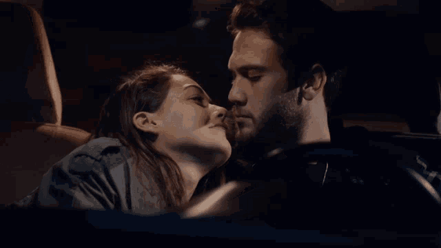 a man and a woman are kissing in a car at night