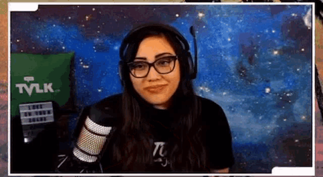 a woman wearing glasses and headphones is smiling in front of a microphone .
