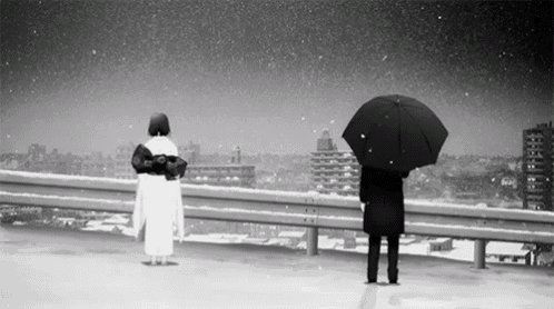 a black and white photo of a man and a woman holding umbrellas in the snow .