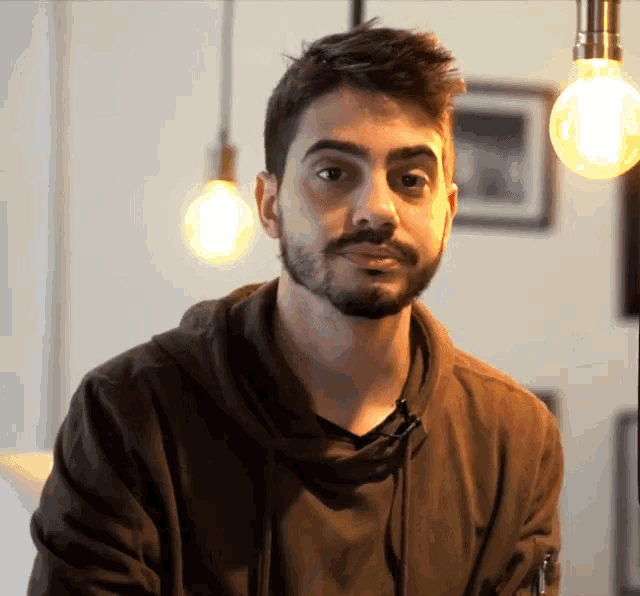 a man with a beard is wearing a brown sweatshirt