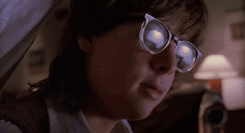 a close up of a person wearing glasses and a white shirt .