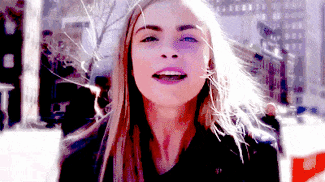 a close up of a woman 's face with a blurry background of buildings