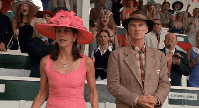 a woman in a pink dress is standing next to a man in a suit