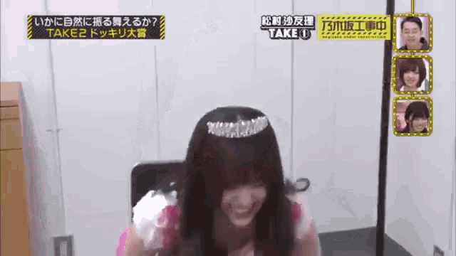 a woman wearing a tiara is sitting in front of a television screen that says take u.