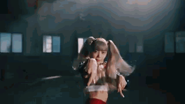 a woman is dancing in a dark room with her hands in the air .