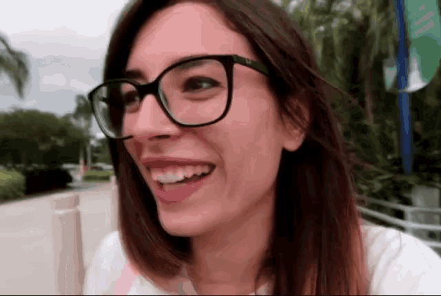 a woman wearing glasses is smiling and looking to the side