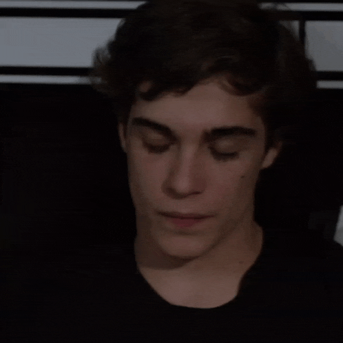 a young man with his eyes closed looks down
