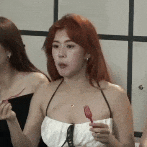a woman in a white top is holding a fork in her hand and eating .