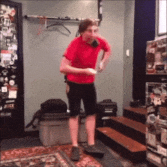 a man in a red shirt is standing on a skateboard in a room