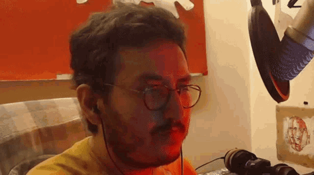 a man wearing glasses and headphones is sitting in front of a microphone in a room .
