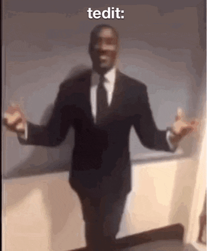 a man in a suit and tie is dancing with his arms outstretched in front of a white board .