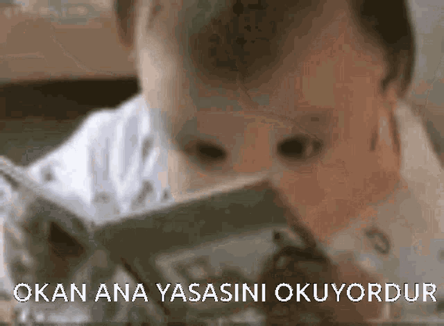 a baby is reading a book with the words okan ana yasasini okuyordur on the bottom