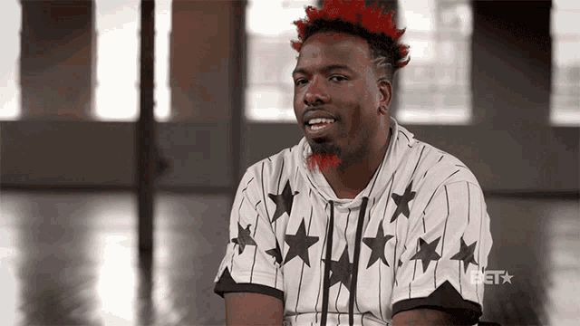a man with red hair is wearing a white and black shirt with black stars