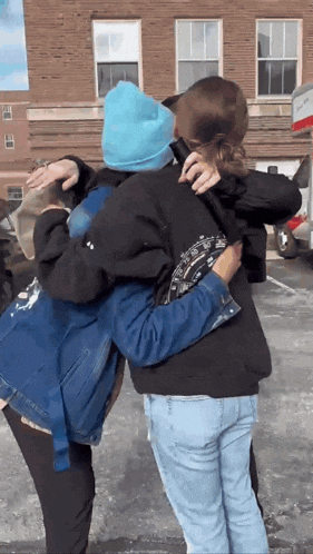 a man in a blue hat is hugging a woman in a black jacket