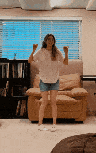 a woman in a white shirt and shorts is dancing in front of a window