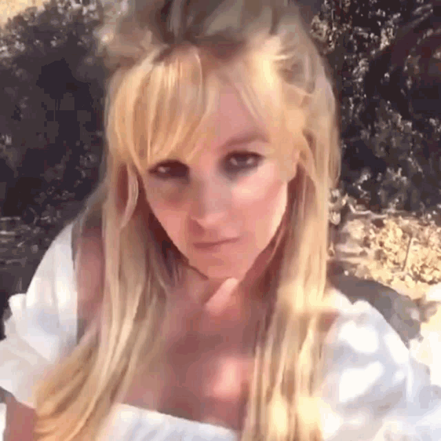 a close up of a woman 's face with blonde hair and a white shirt .