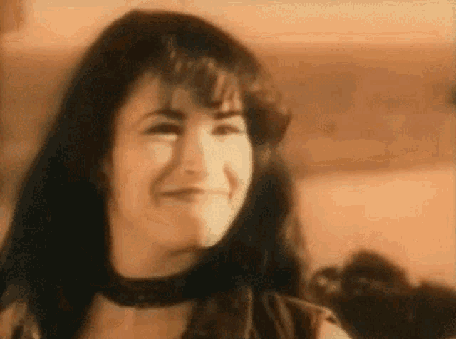a woman with long black hair and a choker is smiling .