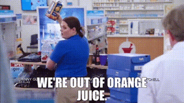 a woman in a blue shirt is holding a can of orange juice in her hand .