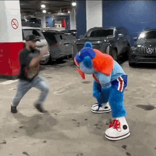 a man is standing next to a mascot in a parking lot .