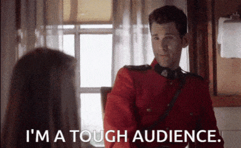 a man in a red uniform is talking to a woman and says `` i 'm a tough audience ''