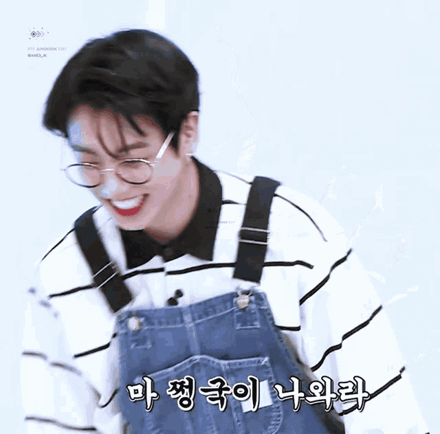 a young man wearing overalls and glasses is smiling in a korean language