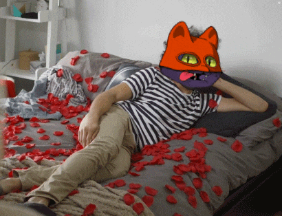 a man wearing a cat mask is laying on a bed