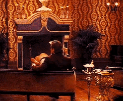 a man sits on a couch in front of a fireplace in a living room