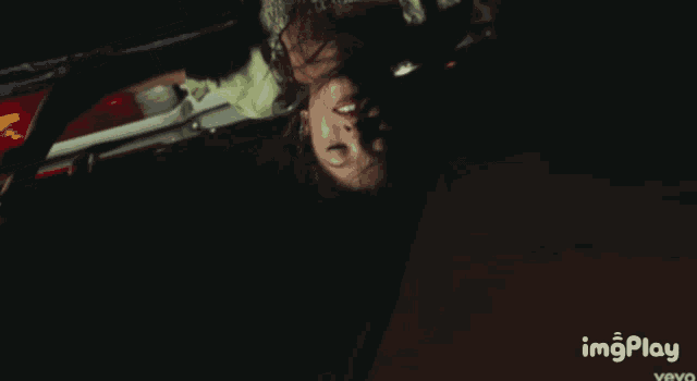 a woman is laying upside down in a dark room with imgplay written on the bottom