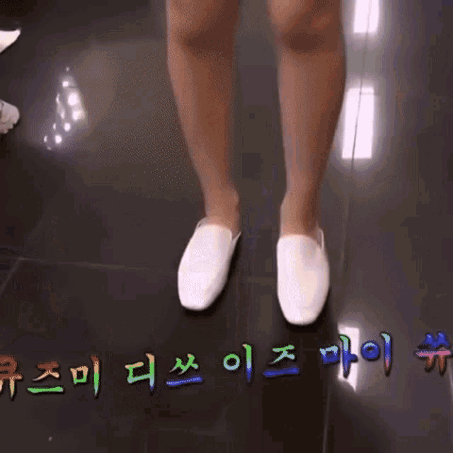 a woman 's legs are shown in a blurry photo with korean writing on the floor .