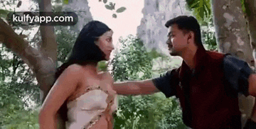 a man and woman are standing next to each other in a forest .