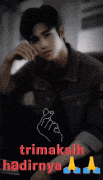 a man in a denim jacket making a heart sign with his hands