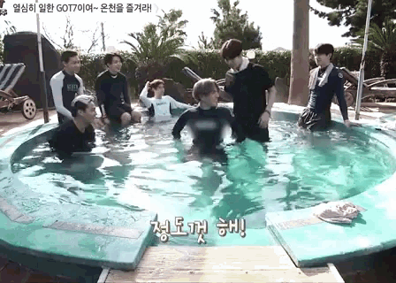 a group of people are standing in a swimming pool with chinese writing on the side