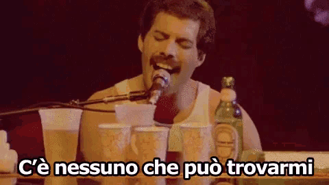 freddie mercury is singing into a microphone while holding a bottle of liquor
