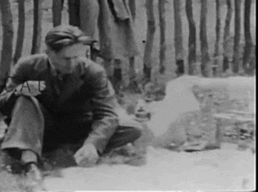 a man in a suit is kneeling down in front of a fence