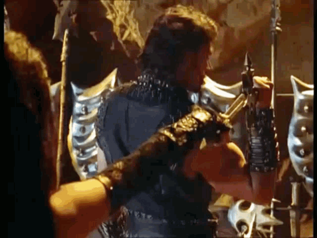 a man in armor is holding a sword and a spear