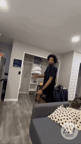 a man in a black shirt is standing in a living room with a sign that says audience