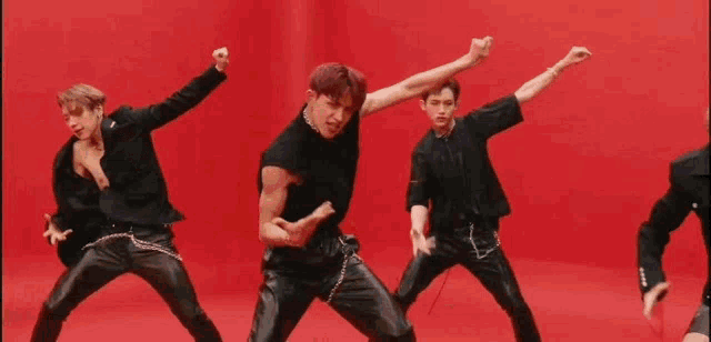 a group of young men are dancing together in front of a red background .