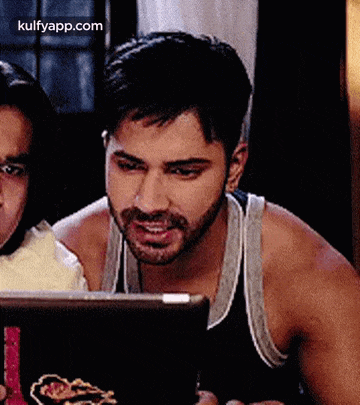 a man with a beard is looking at a tablet while sitting next to a woman .
