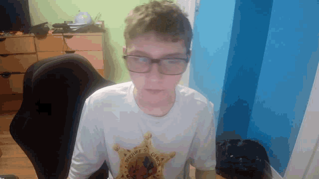 a boy wearing glasses and a shirt that says sheriff 's office on it