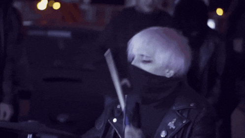 a man with white hair is playing drums in a dark room .