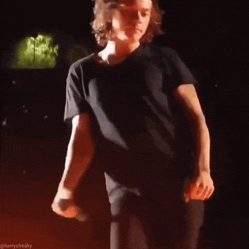 a man in a black shirt is holding a microphone and dancing on stage .