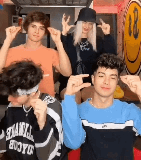 a group of young people are making funny faces with their hands in front of a smiley face .