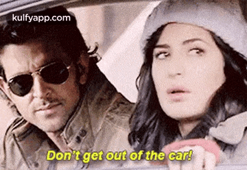 a man and a woman are sitting in a car and the woman is driving .